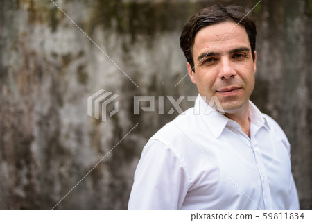 Handsome Persian businessman against concrete wall outdoors Handsome Persian businessman against concrete wall outdoors 59811834