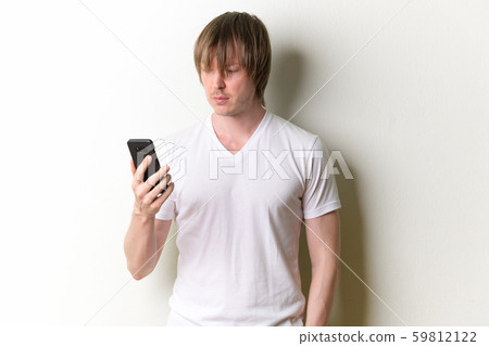 Portrait of young handsome man with long hair using phone Portrait of young handsome man with long hair using phone 59812122