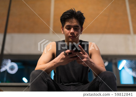 Young handsome Asian man using phone in the city outdoors at night Young handsome Asian man using phone in the city outdoors at night 59812841