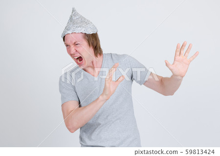 Stressed young man with tinfoil hat as conspiracy theory concept looking scared 59813424
