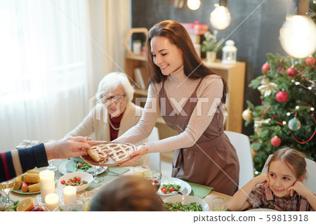 Happy young woman giving homemade pie to her father over served festive table Happy young woman giving homemade pie to her father over served festive table 59813918