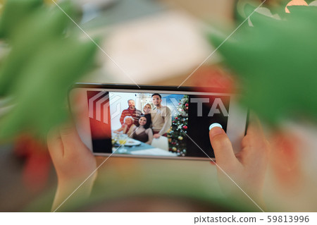 Hands of child holding smartphone while taking photo of happy family by dinner 59813996