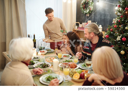 Happy young man bringing homemade pie for his big family having dinner 59814300