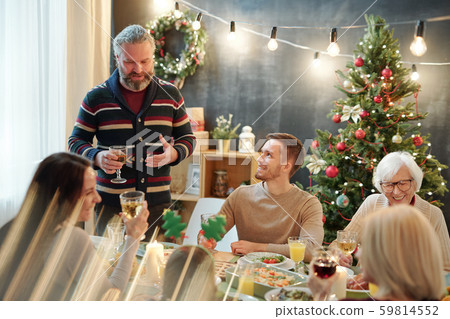 Bearded man with glass of wine pronouncing xmas toast in front of his family 59814552