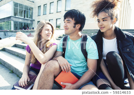 cute group of teenages at the building of university with books huggings, diversity nations real 59814633