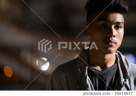 Face of young Asian man thinking in the city streets at night Face of young Asian man thinking in the city streets at night 59814637