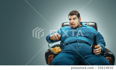 Fat man sitting in a brown armchair, emotional watching TV Fat man sitting in a brown armchair, emotional watching TV 59814650