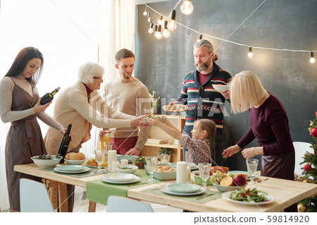 Cute little girl passing bowl with salad to her great grandma by festive table 59814920
