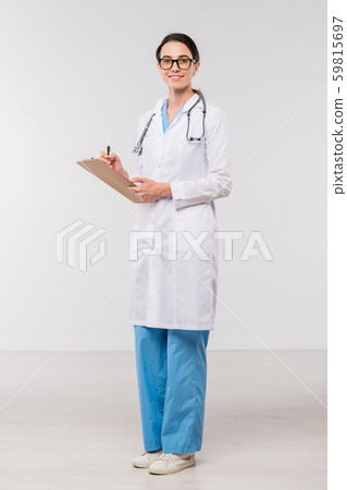 Young confident clinician in whitecoat filling in medical document in isolation 59815697