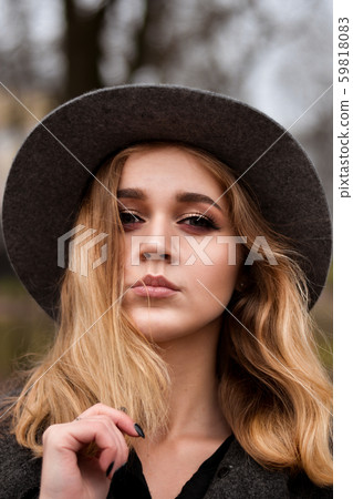 Portrait of beautiful woman wearing hat and gray coat. Outdoor portrait in city 59818083