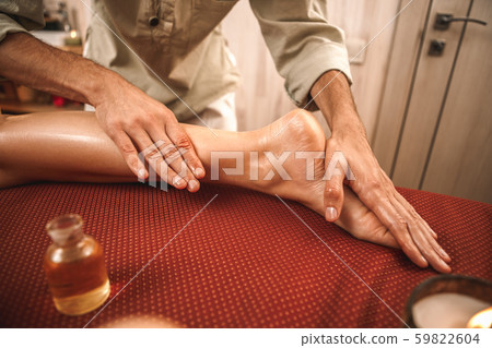 Alternative Medicine. Therapist healing woman doing abhyanga massage with oil on feet close-up 59822604