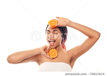 Beauty Concept. Young african woman wearing top isolated on white with orange halves posing singing Beauty Concept. Young african woman wearing top isolated on white with orange halves posing singing 59822624