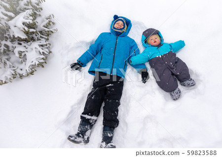 Two boys, 8 and 0 years old, lie in a clean white 59823588