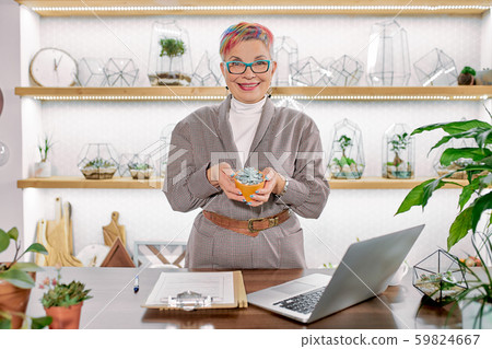 Careful woman in blazer holding plant in pot Careful woman in blazer holding plant in pot 59824667