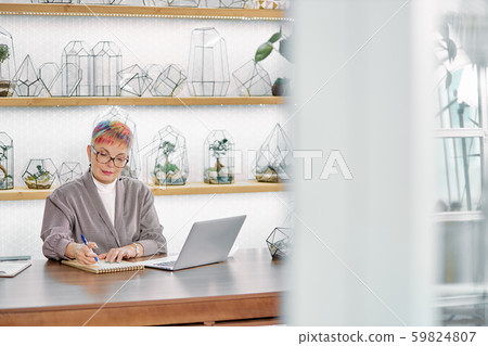 Serious senior business woman writing work issues in notebook Serious senior business woman writing work issues in notebook 59824807