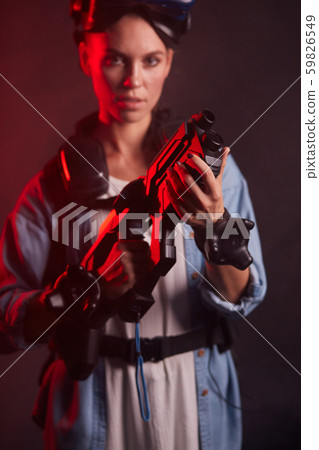 Futuristic woman in headset for virtual reality game holding controller like weapon Futuristic woman in headset for virtual reality game holding controller like weapon 59826549
