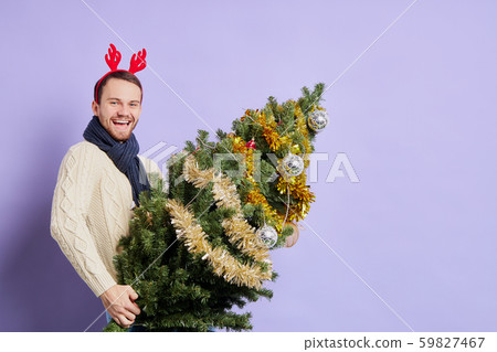 Man in red christmas horn holding Christmas tree Man in red christmas horn holding Christmas tree 59827467