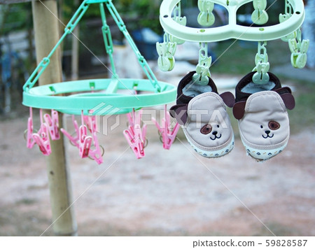 Baby shoes hanging on outdoor clothes hangers. 59828587