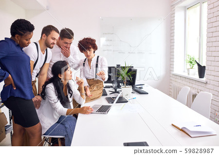 Excited diverse people sit at office desk look at laptop screen Excited diverse people sit at office desk look at laptop screen 59828987