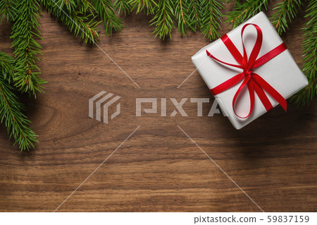 Top view of green spruce twigs with gift box with red ribbon on walnut wood surface 59837159