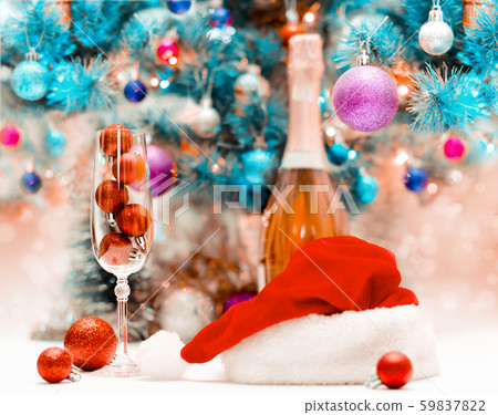 red glitter balls in a large wine glass against the background of a decorated blue Christmas 59837822