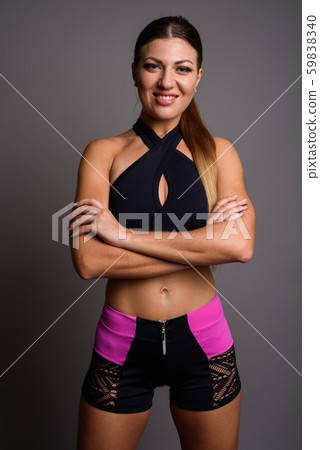 Young beautiful woman ready for gym against gray background Young beautiful woman ready for gym against gray background 59838340