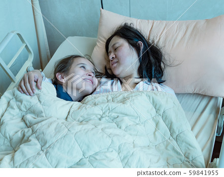 Mother and daughter laying in hosital bed together 59841955