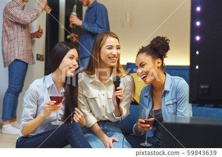 Group of friends having party indoors fun together girls laughing 59843639