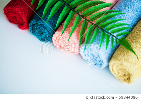 Colored towels and fern leaves on white table with copy space on bath room background. 59844080