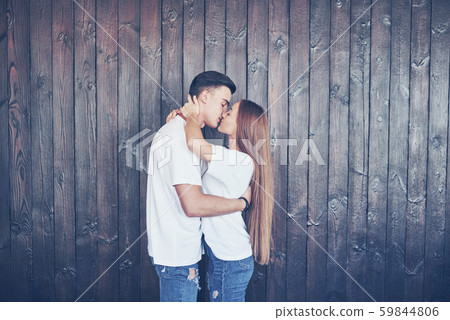 Young couple, guy and girl together on a wooden wall background. They are happy together and dressed 59844806