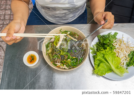 Woman using chopsticks while eating Vietnam Pho chicken noodles Woman using chopsticks while eating Vietnam Pho chicken noodles 59847201