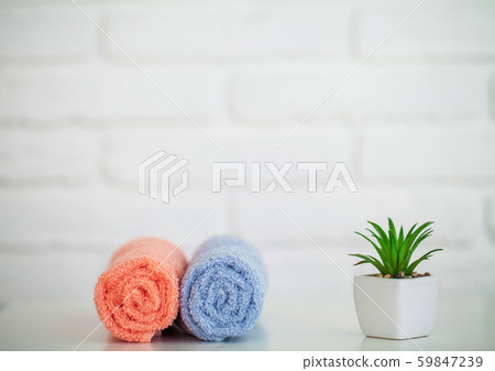 Fluffy bath towels on light wooden table with decor and white background 59847239
