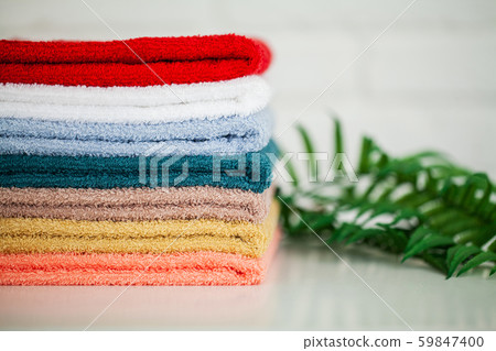 Colorful cotton towels in bathroom on white wooden table Colorful cotton towels in bathroom on white wooden table 59847400