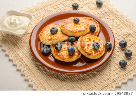 Homemade cheesecakes on a plate with berries and syrup close-up. Healthy food Homemade cheesecakes on a plate with berries and syrup close-up. Healthy food 59848987