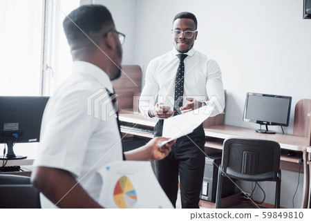 Discussing a project. Two black business people in formalwear discussing something while one of them Discussing a project. Two black business people in formalwear discussing something while one of them 59849810