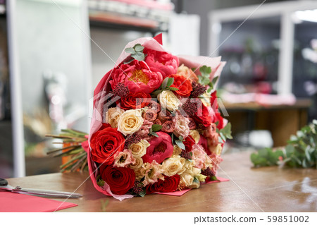 European floral shop concept. Florist woman creates red beautiful bouquet of mixed flowers. Handsome European floral shop concept. Florist woman creates red beautiful bouquet of mixed flowers. Handsome 59851002