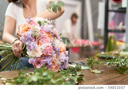 European floral shop concept. Florist woman creates beautiful bouquet of mixed flowers. Handsome 59851037