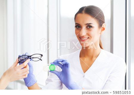 Vision concept. Eye doctor choosing between eyeglasses and lenses standing in front of the eye chart 59851053