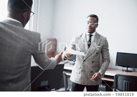 Discussing a project. Two black business people in formalwear discussing something while one of them 59851819
