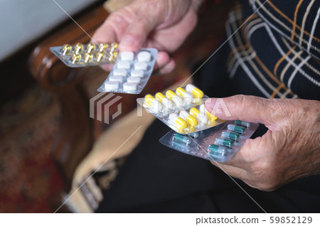 Closeup of a tablet on the hands of an old woman. The concept of choosing medication in old age Closeup of a tablet on the hands of an old woman. The concept of choosing medication in old age 59852129