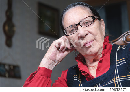 Portrait of an elderly pensive woman in glasses leaning on her arm indoors sitting and thinking Portrait of an elderly pensive woman in glasses leaning on her arm indoors sitting and thinking 59852371