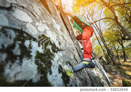 A free aged male climber hangs on a rock wall in a forest in the mountains. Mature Sports Concept 59852640