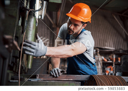 Portrait of a young worker in a hard hat at a large waste recycling factory. The engineer monitors Portrait of a young worker in a hard hat at a large waste recycling factory. The engineer monitors 59853883