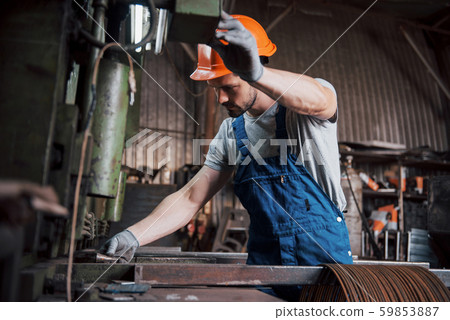 Portrait of a young worker in a hard hat at a large metalworking plant. The engineer serves the 59853887