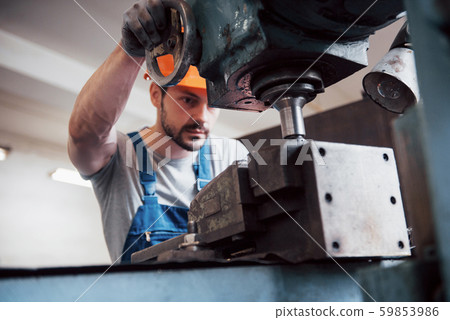 Portrait of a young worker in a hard hat at a large waste recycling factory. The engineer monitors 59853986