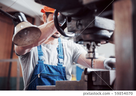 Portrait of a young worker in a hard hat at a large waste recycling factory. The engineer monitors 59854070