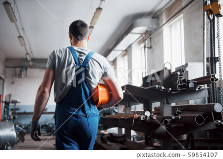 Portrait of a young worker in a hard hat at a large waste recycling factory. The engineer monitors 59854107