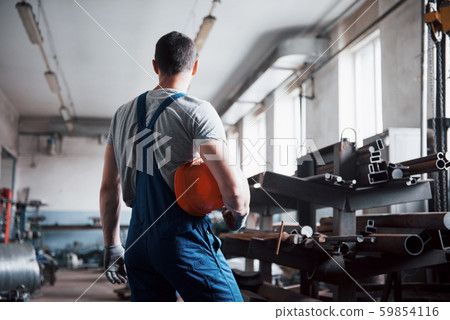 Portrait of a young worker in a hard hat at a large waste recycling factory. The engineer monitors Portrait of a young worker in a hard hat at a large waste recycling factory. The engineer monitors 59854116