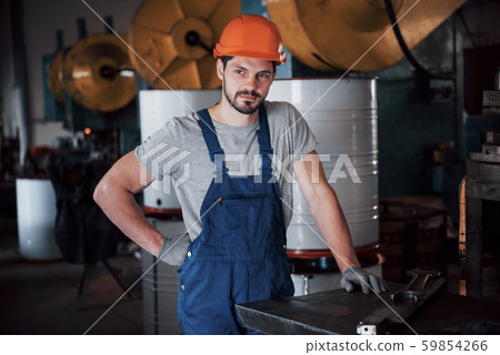 Portrait of a young worker in a hard hat at a large waste recycling factory. The engineer monitors Portrait of a young worker in a hard hat at a large waste recycling factory. The engineer monitors 59854266
