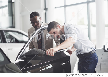 An African man who buys a new car checks a car talking to a professional vendor. 59855129